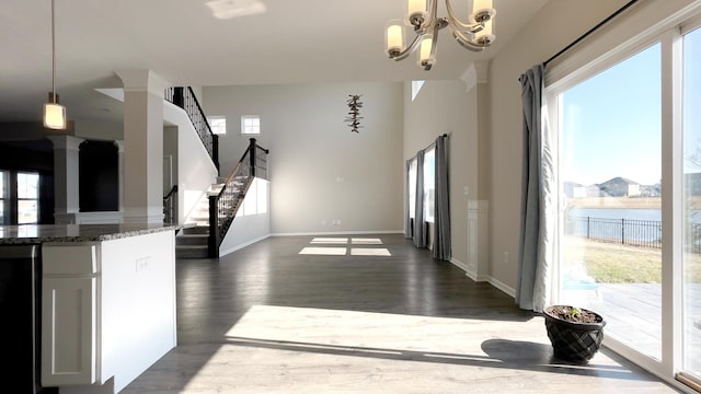 interior space with dark wood-style floors, a healthy amount of sunlight, stone countertops, and a chandelier