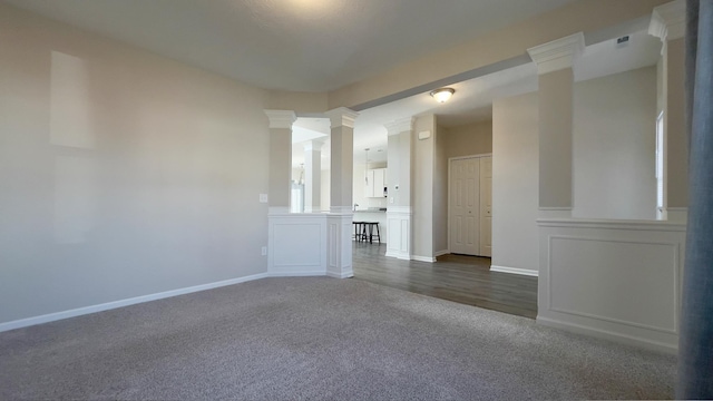 spare room featuring visible vents, decorative columns, baseboards, and dark colored carpet