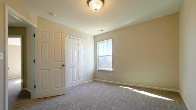 unfurnished bedroom featuring carpet, visible vents, a closet, and baseboards