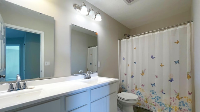 bathroom with double vanity, toilet, and a sink