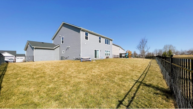 rear view of property featuring a lawn, a fenced backyard, and a playground