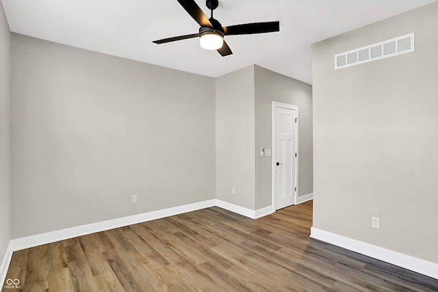 unfurnished room with a ceiling fan, visible vents, baseboards, and wood finished floors