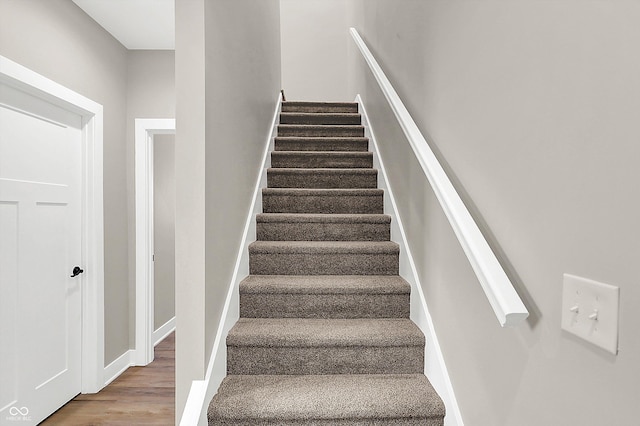 staircase featuring wood finished floors and baseboards