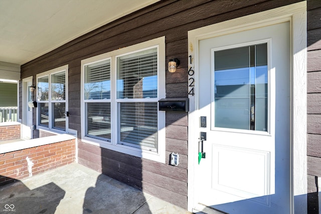 doorway to property featuring covered porch and brick siding