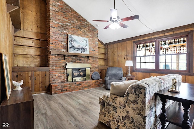 living area featuring a fireplace, vaulted ceiling, wood walls, and wood finished floors