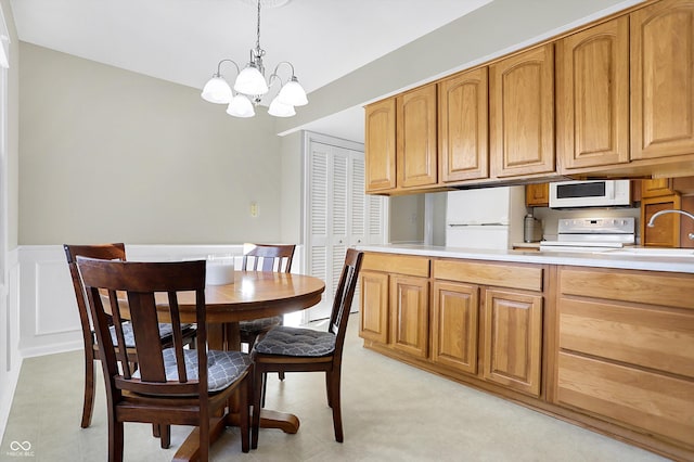 kitchen with white appliances, hanging light fixtures, a sink, light countertops, and a notable chandelier