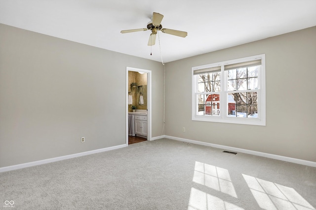 unfurnished bedroom with baseboards, visible vents, a ceiling fan, ensuite bath, and carpet floors