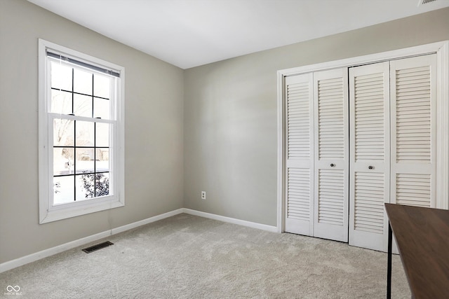 unfurnished bedroom with baseboards, visible vents, a closet, and light colored carpet