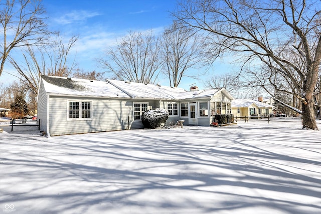 snow covered house with a chimney and fence