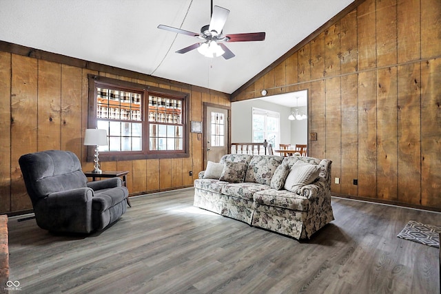 living area with vaulted ceiling, wood walls, and wood finished floors