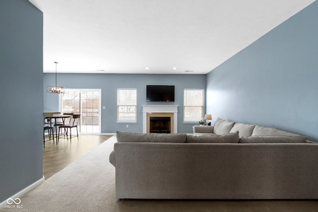 living room featuring light carpet, baseboards, a fireplace, a notable chandelier, and recessed lighting