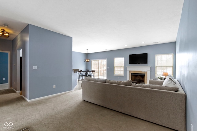 living room featuring light carpet, a fireplace, and baseboards