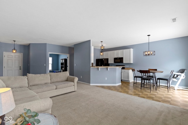 living area featuring light carpet, baseboards, visible vents, and a notable chandelier