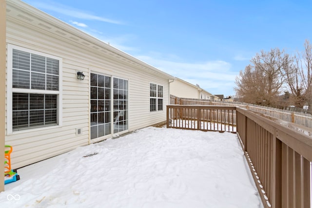 snow covered deck with a fenced backyard