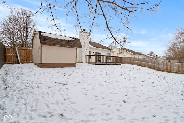 yard layered in snow featuring a fenced backyard and a wooden deck