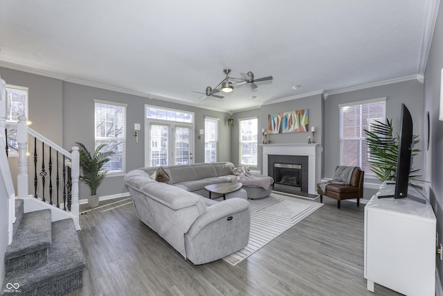 living room featuring light wood-style flooring, stairs, ornamental molding, and a fireplace with raised hearth