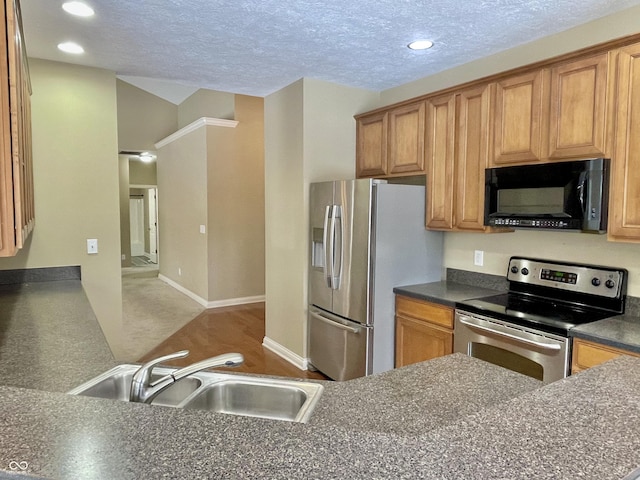 kitchen with a textured ceiling, recessed lighting, stainless steel appliances, a sink, and dark countertops