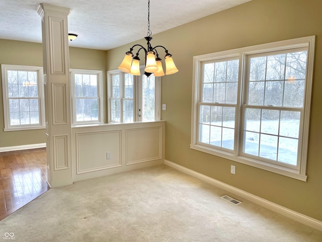 unfurnished dining area with a textured ceiling, carpet, visible vents, and baseboards