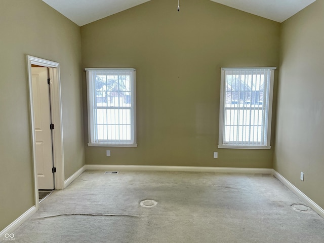 spare room with lofted ceiling, baseboards, visible vents, and carpet