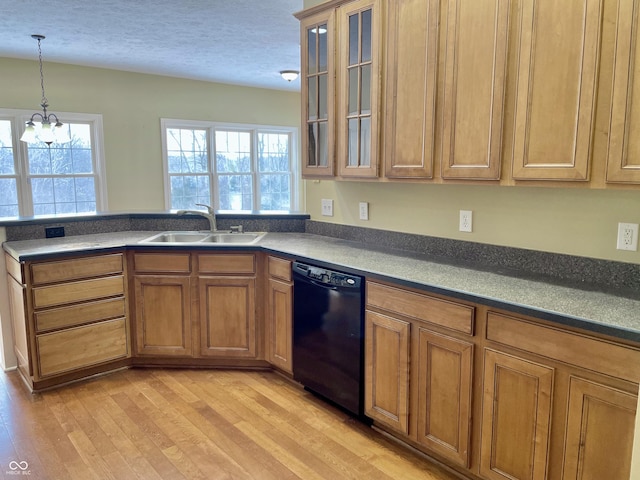 kitchen with brown cabinetry, dishwasher, light wood-style flooring, and a sink