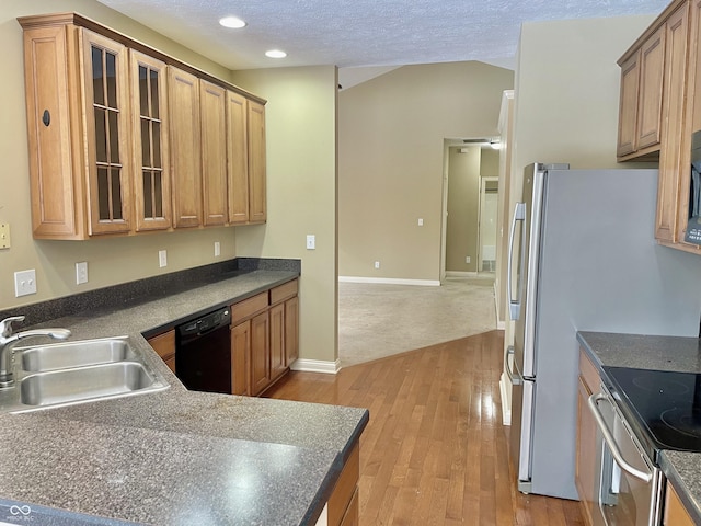 kitchen featuring light wood-style floors, dark countertops, black dishwasher, and a sink