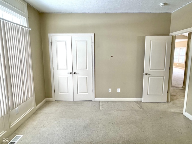 unfurnished bedroom featuring a closet, light colored carpet, visible vents, and baseboards