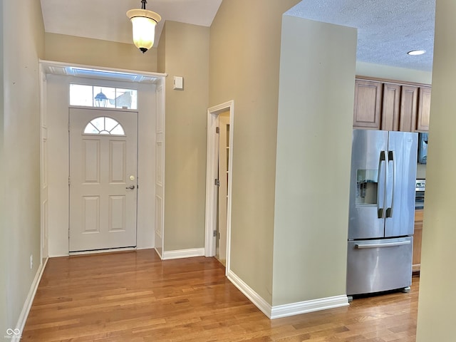 entryway featuring a textured ceiling, light wood-style flooring, and baseboards