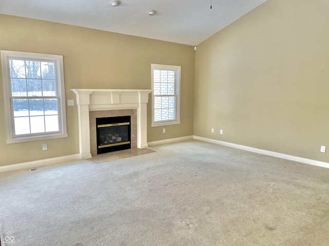 unfurnished living room featuring baseboards, visible vents, a high end fireplace, and light colored carpet