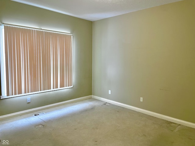 empty room featuring carpet, visible vents, and baseboards