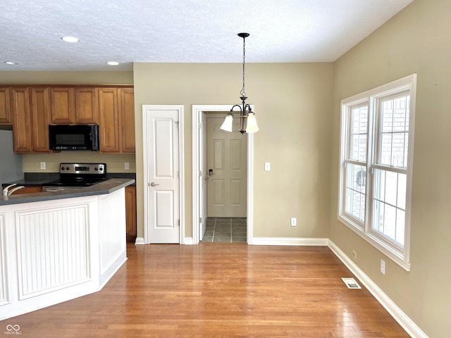 kitchen with visible vents, brown cabinetry, dark countertops, stainless steel range with electric stovetop, and black microwave