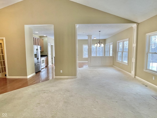 unfurnished living room featuring vaulted ceiling, baseboards, a chandelier, and light colored carpet