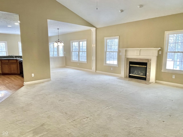 unfurnished living room with light carpet, a sink, a high end fireplace, baseboards, and vaulted ceiling