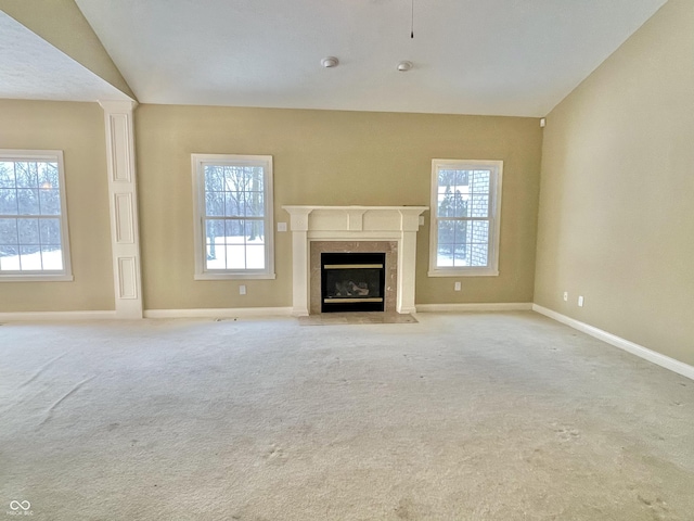 unfurnished living room with a high end fireplace, light carpet, lofted ceiling, and baseboards