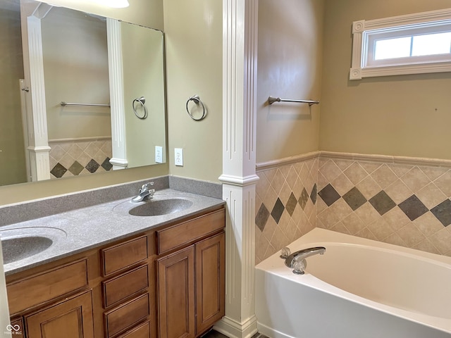 bathroom featuring wainscoting, a garden tub, a sink, and double vanity