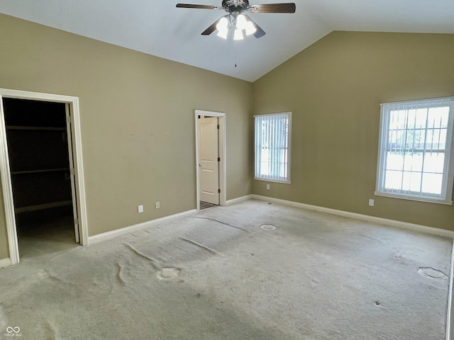 unfurnished bedroom featuring carpet flooring, vaulted ceiling, a spacious closet, and baseboards