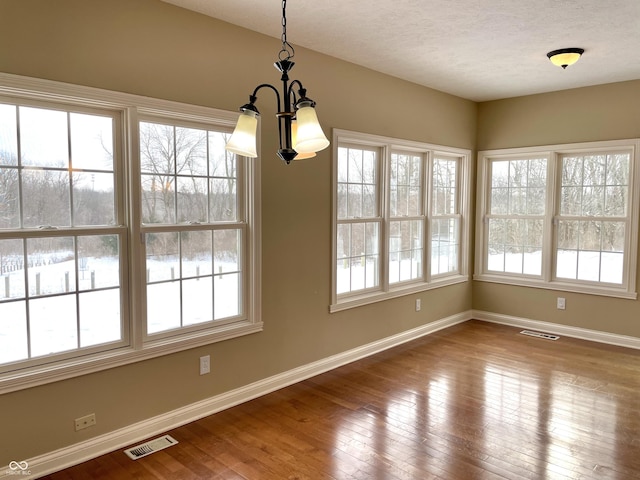 unfurnished dining area with plenty of natural light, wood-type flooring, and visible vents