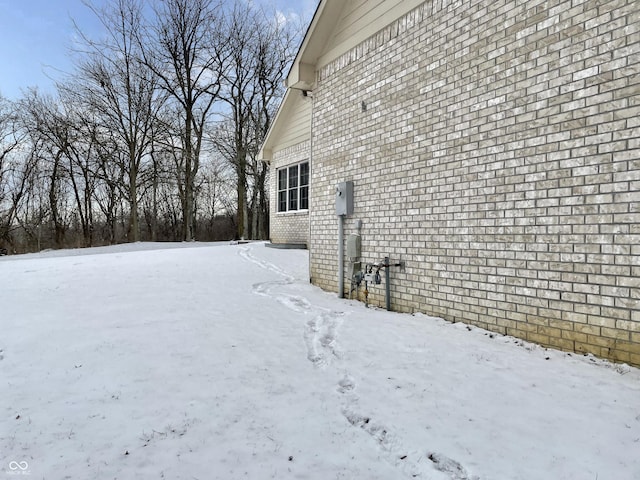 snow covered property with a garage and brick siding