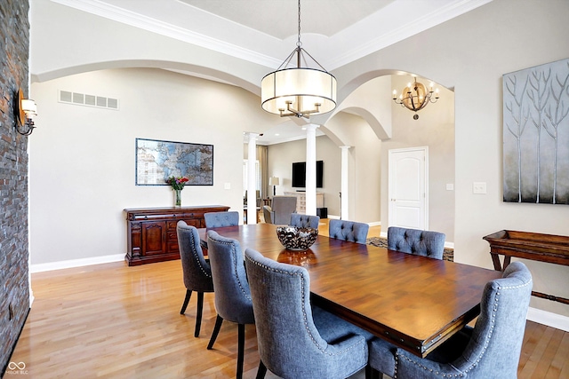 2110 Cheviot Ct, Greenwood, IN 46143 - dining area with decorative columns, arched walkways, light wood-style floors, a high ceiling, and a chandelier