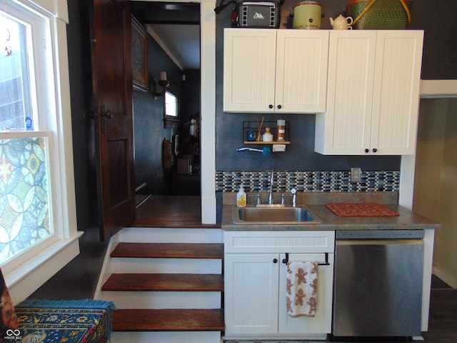 kitchen with tasteful backsplash, white cabinets, dishwasher, and a sink