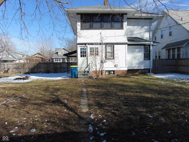 back of property featuring entry steps, a chimney, fence, and a yard