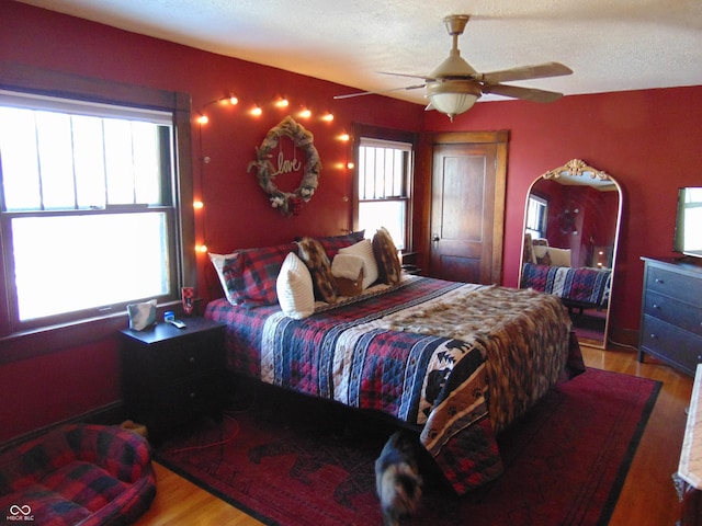 bedroom featuring a textured ceiling, a ceiling fan, and light wood-style floors