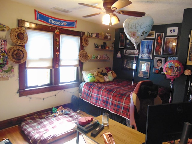 bedroom featuring a ceiling fan, wood finished floors, visible vents, and baseboards