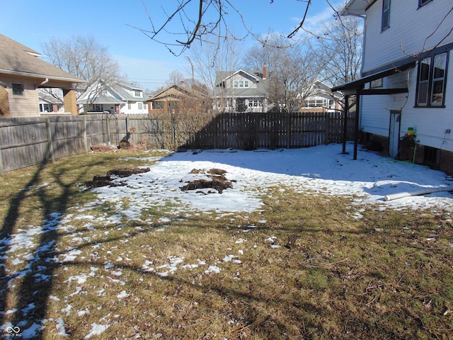 yard layered in snow featuring a residential view and a fenced backyard