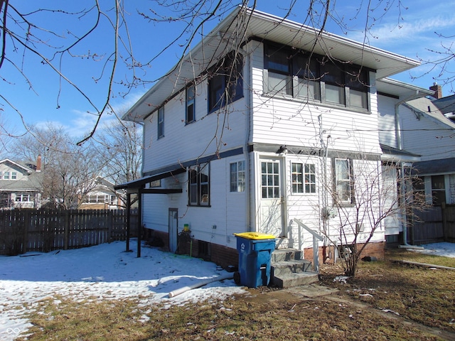 snow covered house with entry steps and fence