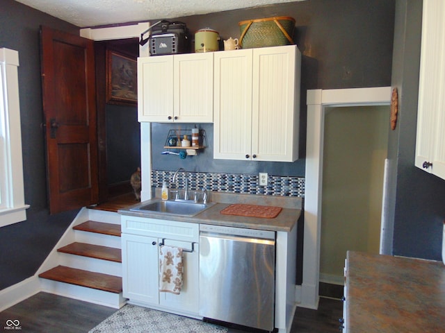 kitchen with tasteful backsplash, white cabinets, a sink, dishwasher, and baseboards