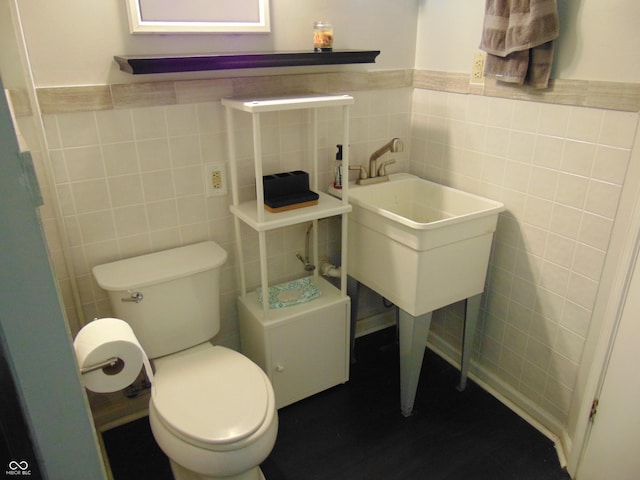 bathroom featuring wainscoting, tile walls, and toilet