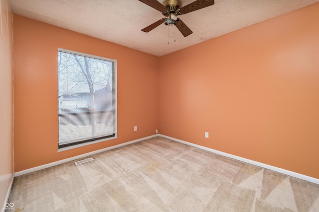 empty room featuring baseboards, light carpet, a textured ceiling, and visible vents