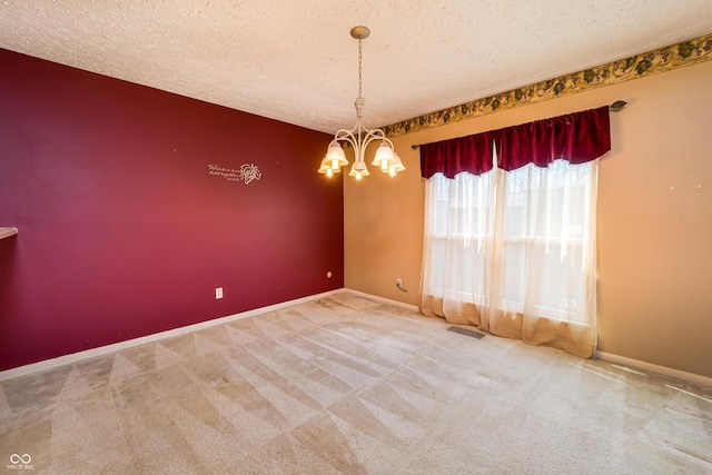 carpeted empty room with baseboards, a notable chandelier, a textured ceiling, and visible vents