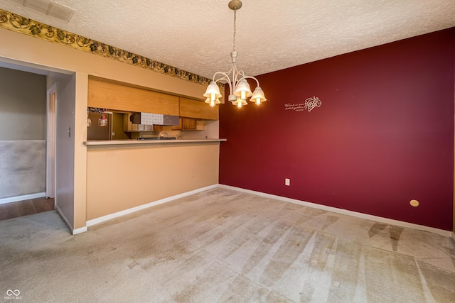 unfurnished dining area featuring visible vents, a notable chandelier, a textured ceiling, carpet floors, and baseboards