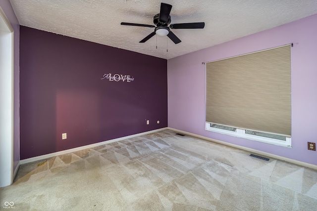 carpeted empty room with baseboards, visible vents, a textured ceiling, and ceiling fan